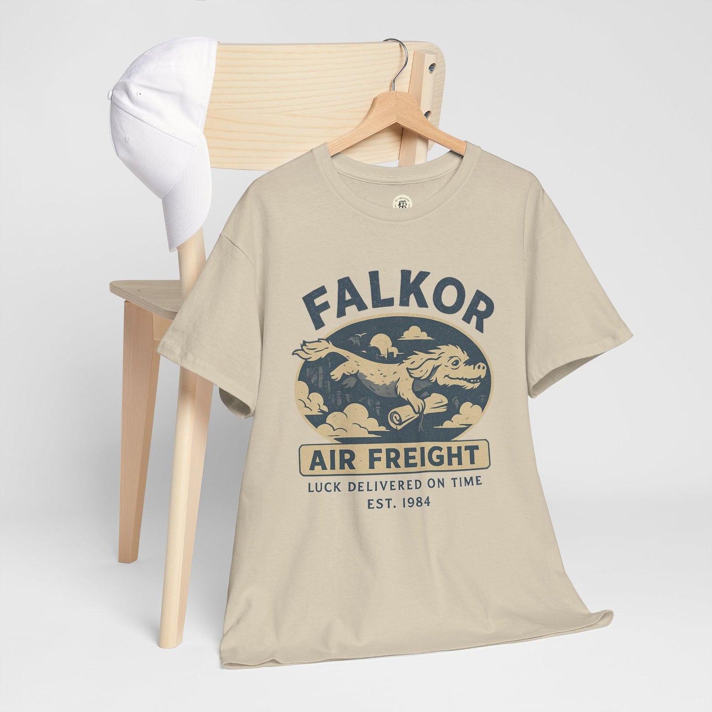 Beige Falkor Neverending Story t-shirt with vintage air freight design hanging on wooden chair