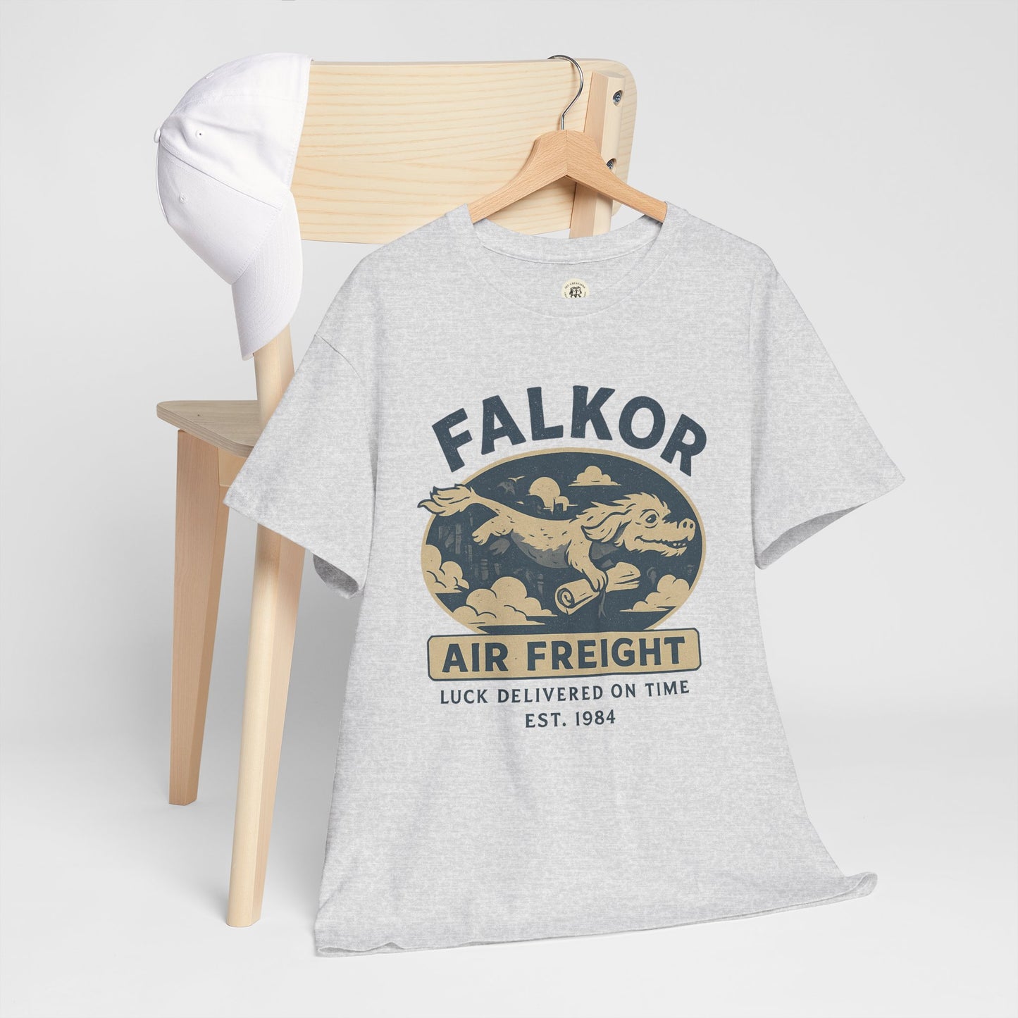 Light gray Falkor Neverending Story t-shirt with vintage air freight design hanging on wooden hanger