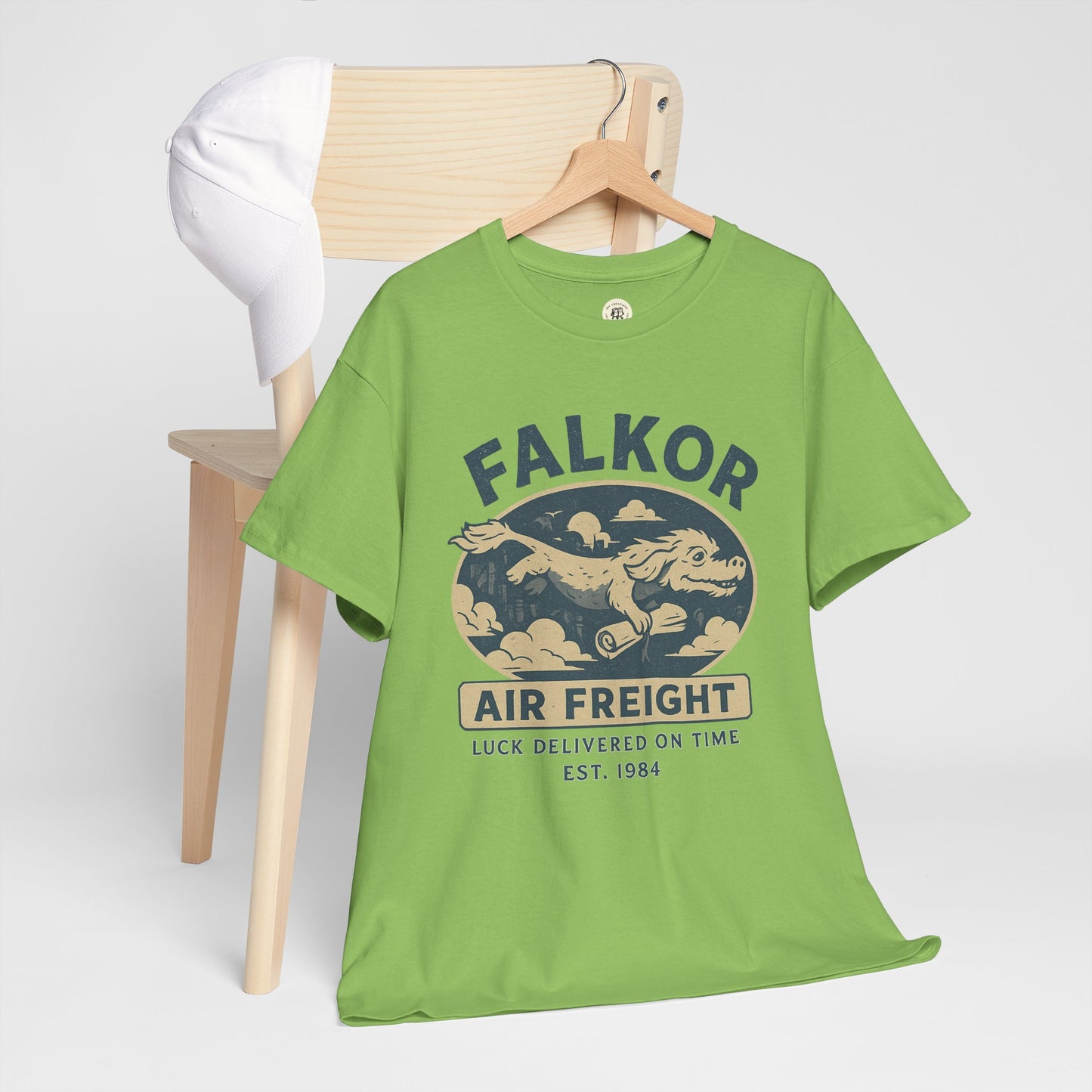 Green Falkor Neverending Story t-shirt with vintage air freight design hanging on wooden chair