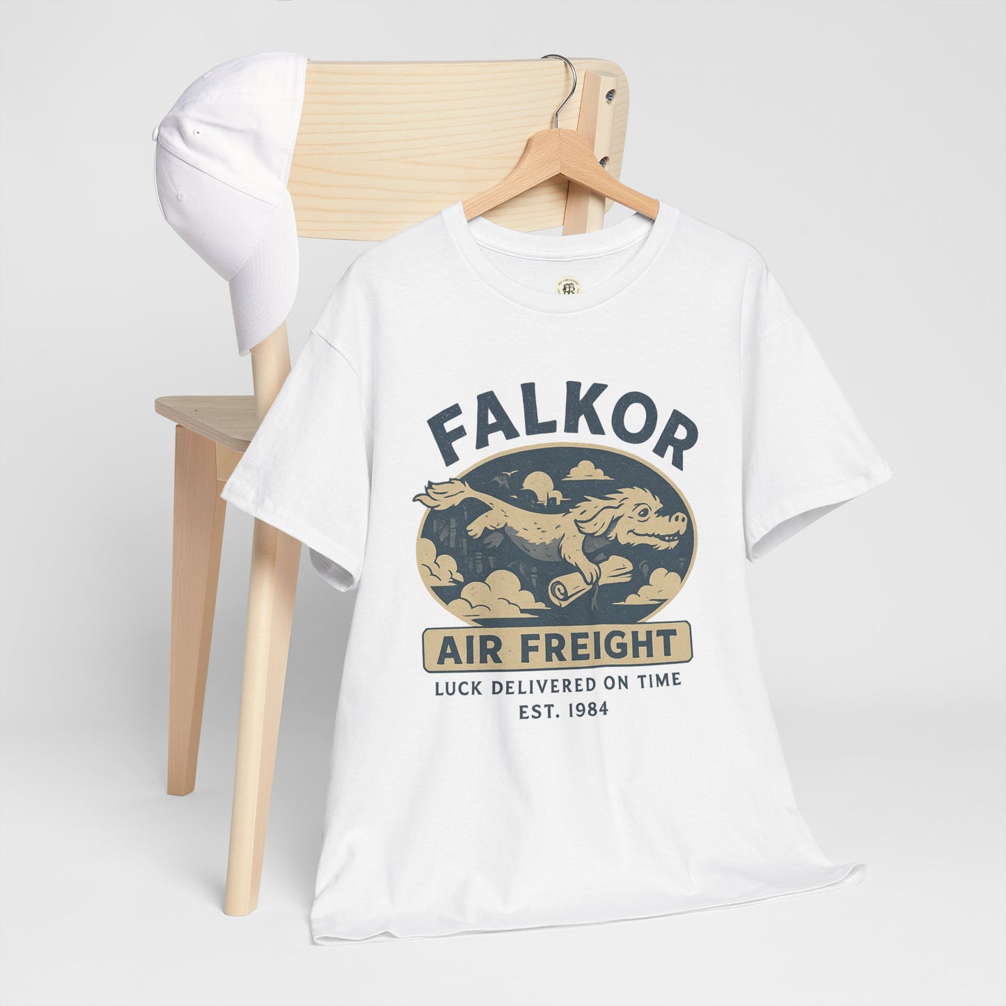 White Falkor Neverending Story t-shirt with vintage dragon air freight design displayed on wooden chair