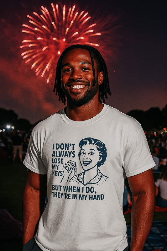 Smiling man wearing a funny key holder t-shirt with humorous text about losing keys at a nighttime fireworks event