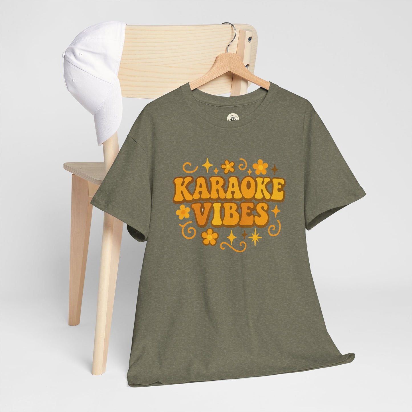 Olive green Printify karaoke vibes t-shirt with retro orange flower and star design hanging on wooden chair