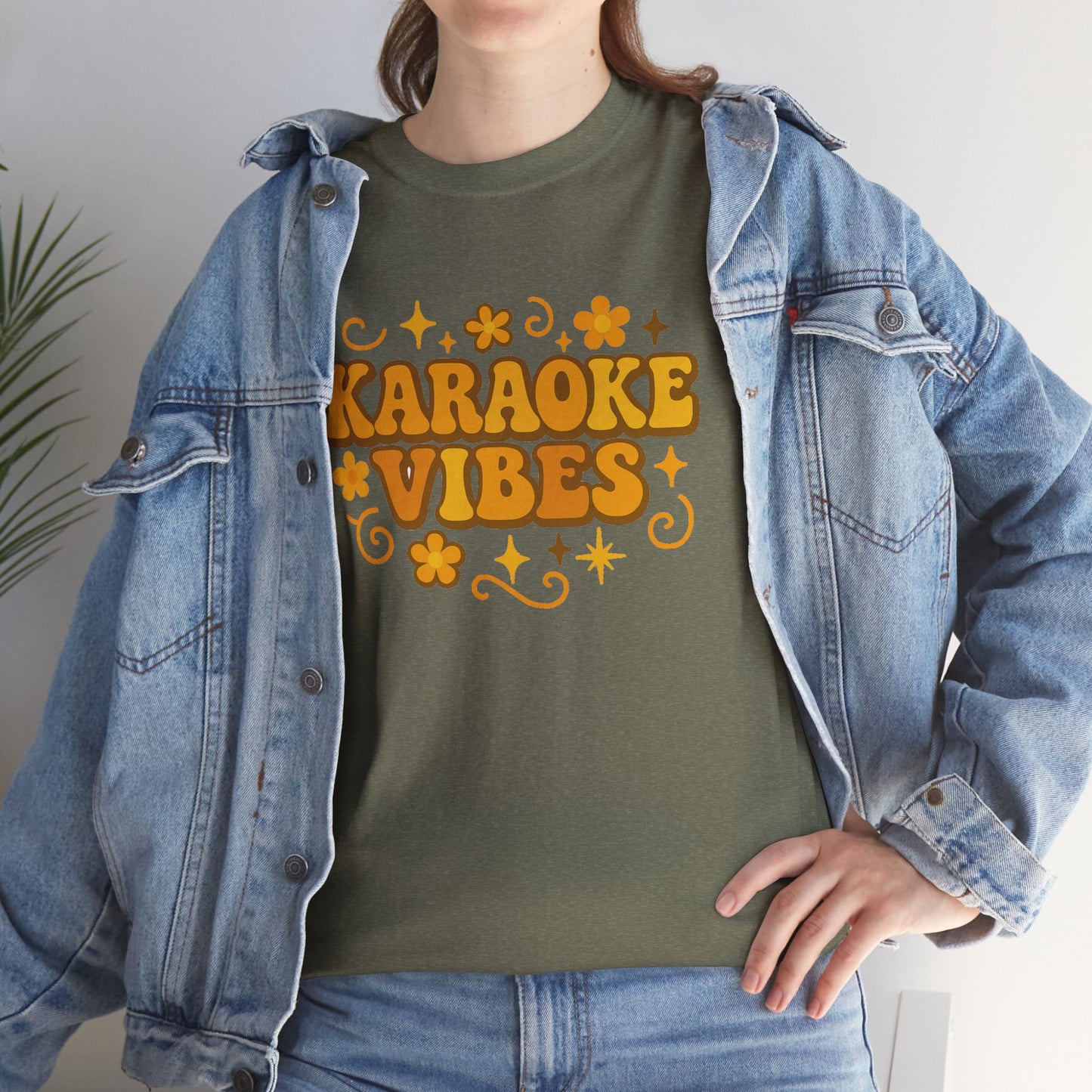 Karaoke vibes t-shirt in olive green with retro orange text and floral design worn with denim jacket