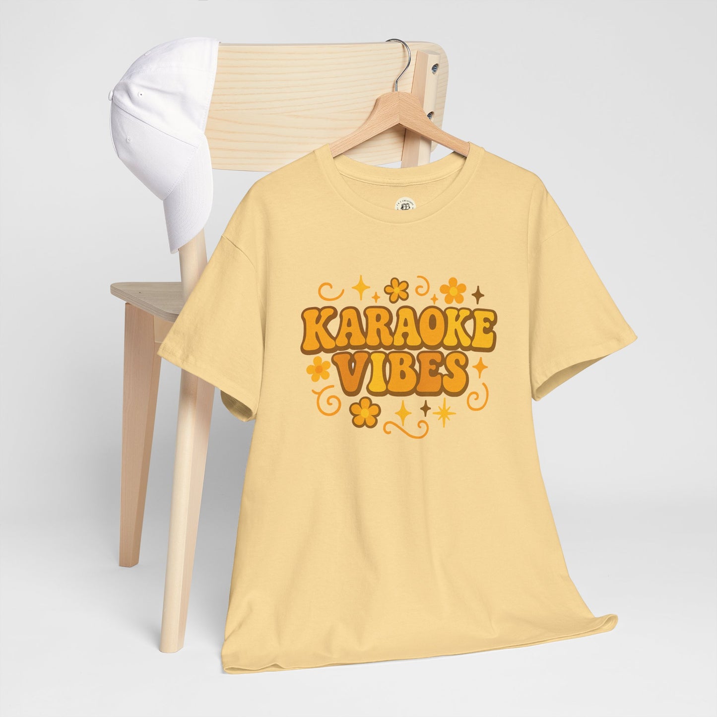 Yellow karaoke vibes t-shirt with retro flower design displayed on wooden chair with white cap