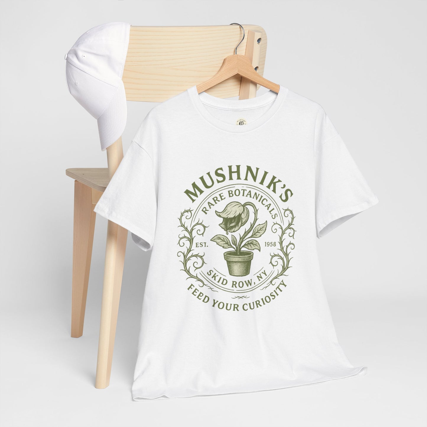White Printify Little Shop of Horrors t-shirt featuring Mushnik's Rare Botanicals design with green plant graphic