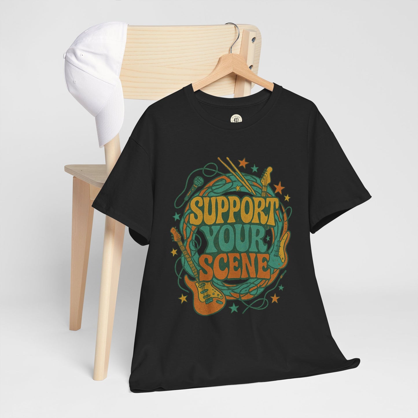 Black Printify support your scene t-shirt with colorful guitar and music design hanging on wooden chair