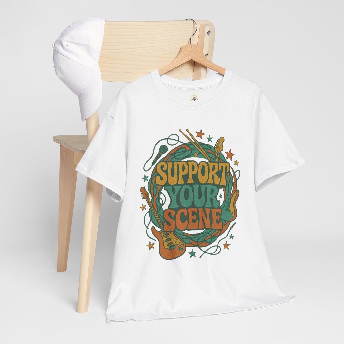 White support your scene t-shirt with guitar and drum graphic hanging on wooden chair with white cap