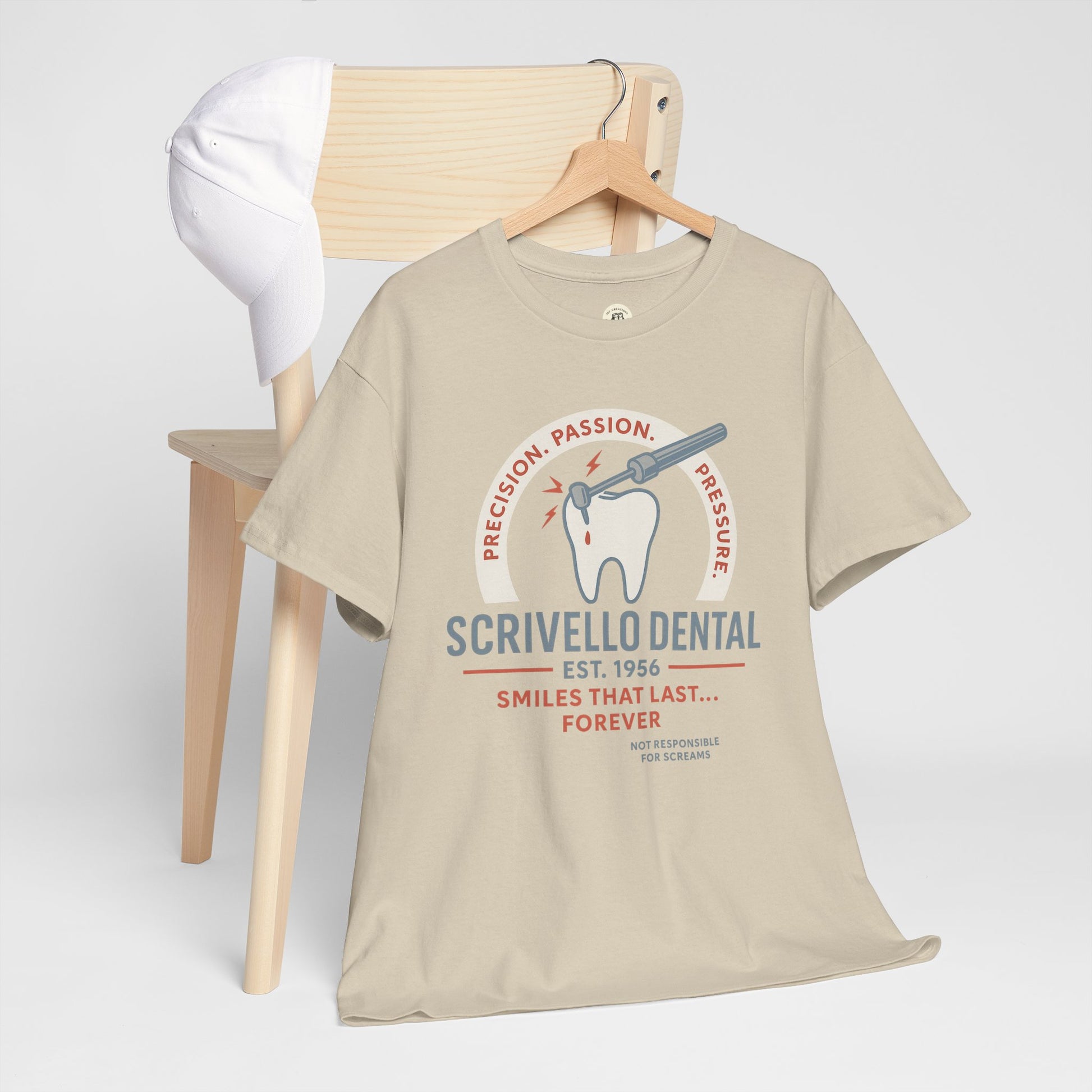 Printify beige Little Shop of Horrors t-shirt with dental graphic and text hanging on wooden chair